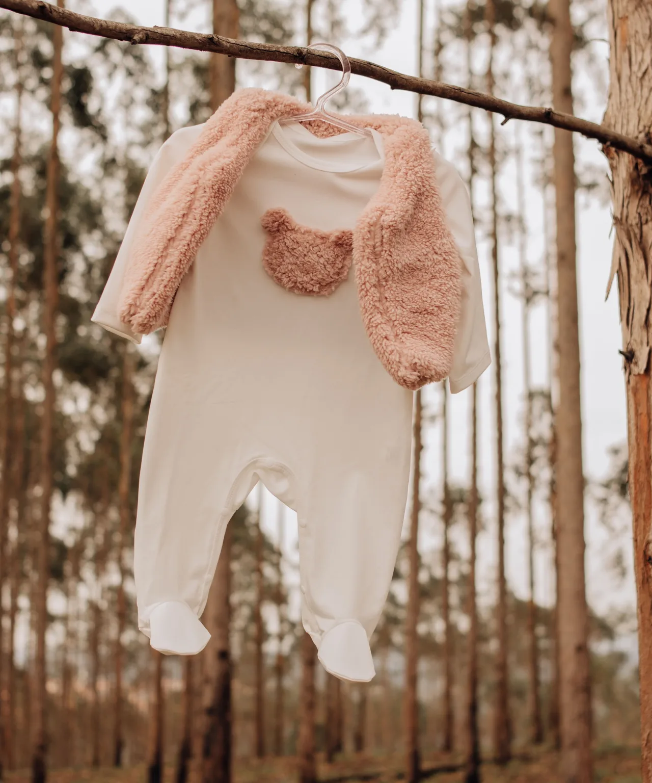 Baju tidur bayi warna krem dengan beruang di dada dan kardigan bulu, tergantung di dahan